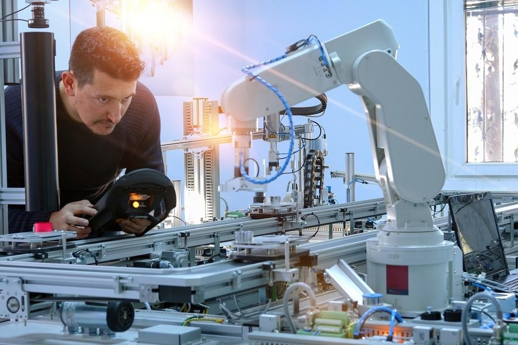 mężczyzna programuje automatycznego robota przemysłowego